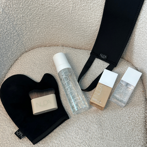Self Tan Back Applicator | NUDA set including applicator mitt, brush, spray bottle, and tanning products displayed on a textured fabric surface for skincare and body care use.