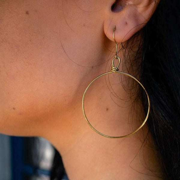 Close-up of a person wearing Olivia Hoop Earrings | Purpose Jewelry, featuring a simple, elegant gold-tone circular hoop design that complements the natural skin tone.