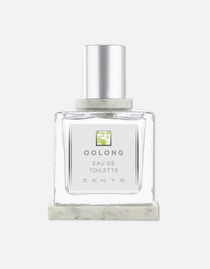 Clear glass bottle of Eau de Toilette | Zents with silver cap and minimalist label featuring green floral design and clean typography on white background.