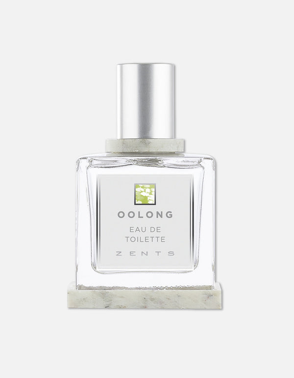 Clear glass bottle of Eau de Toilette | Zents with silver cap and minimalist label featuring green floral design and clean typography on white background.