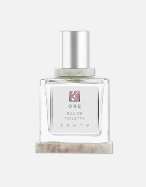 Clear glass bottle of Eau de Toilette | Zents with a silver cap, minimalist label, and light neutral-toned marble base, showcasing a clean and elegant design.