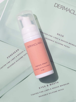 A bottle of Patch Prep Cleanser™ | Dermaclara with a soft pink label placed on packaging that highlights reusable silicone patches for forehead, neck, and eyes & mouth areas, designed to tighten fine lines and reduce wrinkles.