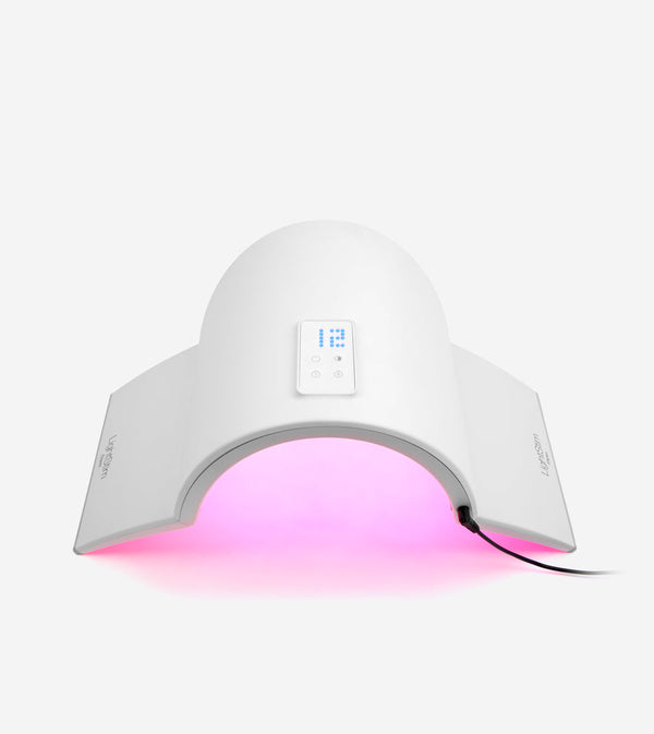 White wellness device Elipsa | LightStim with digital controls and arms emitting pink light for skincare and recovery treatments connected by a power cord