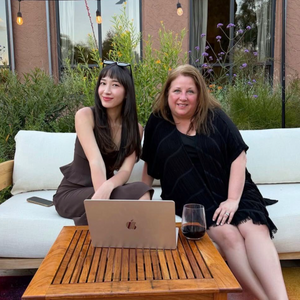 Astrology Lounge (Full Day)- Astrology Readings | Alexa Michaelis featuring two women seated outdoors on a sofa with a laptop and drinks on a wooden table