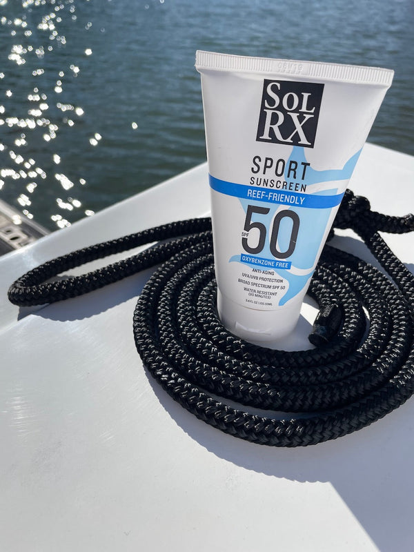 SPORT Sunscreen SPF 50 | SolRX Sunscreen tube standing on a coiled black rope by the water, highlighting sunscreen for active outdoor skincare and reef-friendly SPF protection.