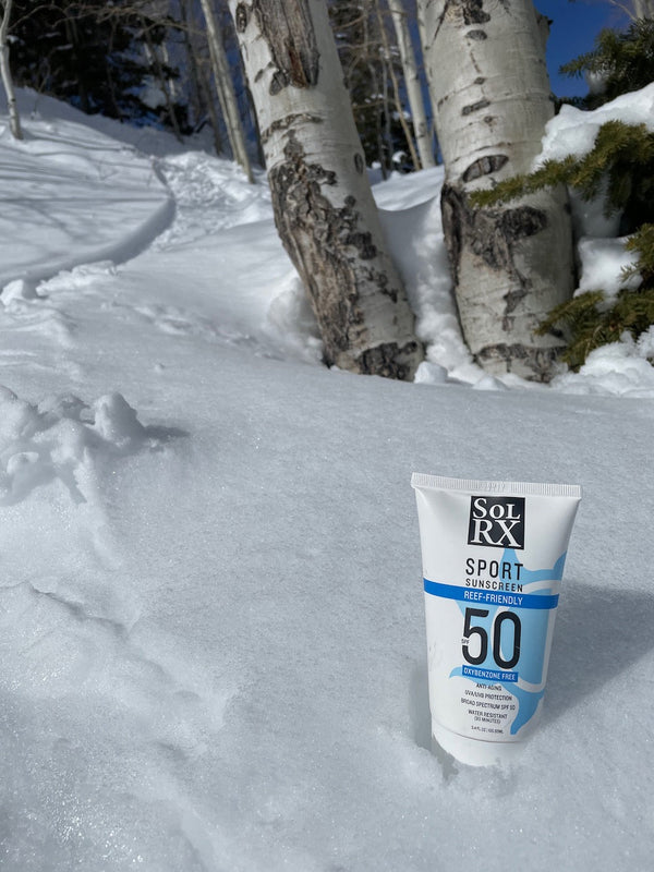 SPORT Sunscreen SPF 50 | SolRX Sunscreen tube placed on snow near birch trees, showcasing skincare product designed for outdoor use and water resistance.