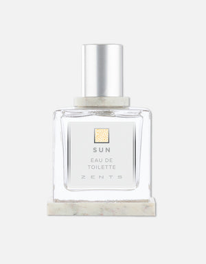 Clear glass bottle of Eau de Toilette | Zents with a silver cap and minimalist label on a marble base against a plain white background.