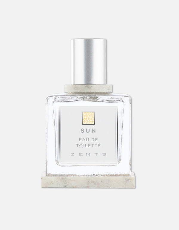 Clear glass bottle of Eau de Toilette | Zents with a silver cap and minimalist label on a marble base against a plain white background.