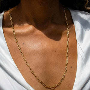 Swing Paperclip Necklace - silver tone | Purpose Jewelry displayed on a model wearing a white satin top, showcasing its elegant chain design and polished finish.