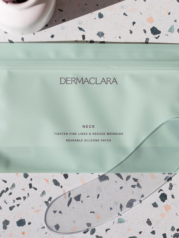 Packaging of the SiliconeFusion™ Neck Patch | Dermaclara displayed on a terrazzo surface with a transparent reusable silicone patch partially visible nearby.