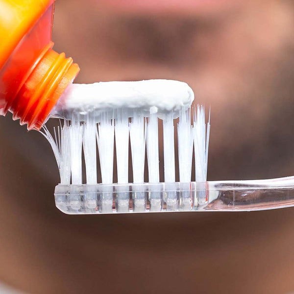 Close-up of toothpaste being applied onto clear bristles of Nano-Silver Toothbrush | LINHART, highlighting hygiene and oral care wellness.
