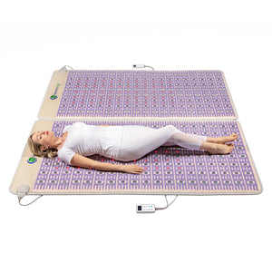 A woman lying relaxed on the TAJ-Mat™ King 8076 Firm - Photon PEMF Split Inframat Pro® | HealthyLine, a wellness device designed for body care and recovery with embedded photon and PEMF therapy features.