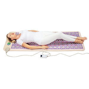 Woman lying on a purple and beige therapeutic wellness mat with a control device, demonstrating relaxation using the TAJ-Mat™ Full 7224 Firm - Photon PEMF InfraMat Pro® | HealthyLine.