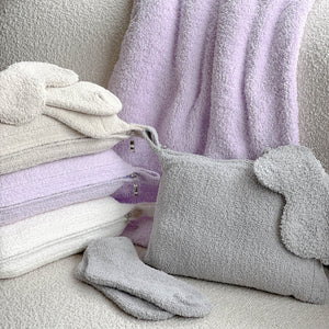 Soft lavender, cream, and gray chenille travel blankets and matching eye masks paired with cozy socks, showcasing the Travel Blankets - Solid - Chenilla Fine™ | Kashwére collection.