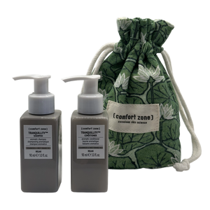 Two pump bottles of shampoo and conditioner labeled Tranquillity alongside a green floral drawstring pouch, part of the Tranquillity Hair Kit | [ comfort zone ] for hair wellness.