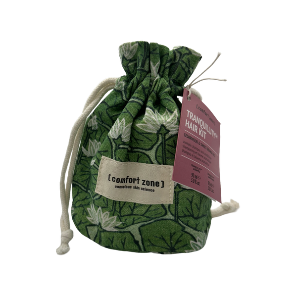 Green patterned drawstring pouch with a label reading [comfort zone] holding the Tranquillity Hair Kit | [ comfort zone ] accompanied by a pink informational tag.