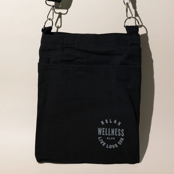 Black fabric mini tote featuring a front pocket and adjustable strap with printed text reading Relax Wellness Club Live Love Spa, designed for easy carrying Wellness Club Mini Tote | Live Love Spa.