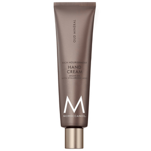 Tube of Hand Cream | Moroccanoil in brown packaging with gold cap, labeled with argan oil and hyaluronic acid for rich nourishment and skincare benefits.
