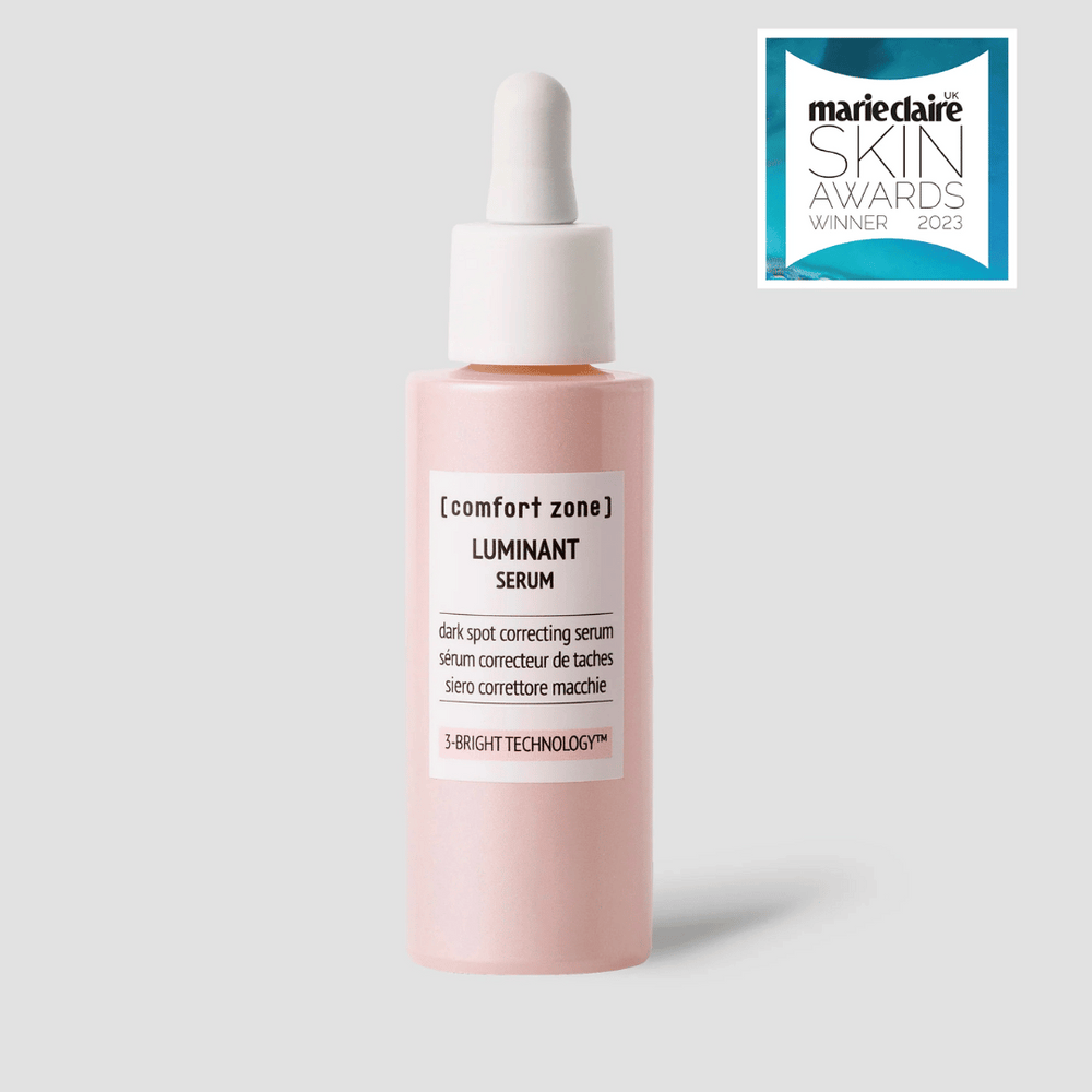 A pink dropper bottle of Luminant Serum | [ comfort zone ], a skincare product designed for dark spot correction using 3-Bright Technology.