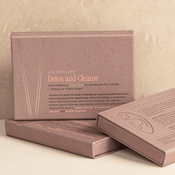 Three elegant rose gold boxes of Detox and Cleanse - 24K Gold Ear Seed | Vie Healing, featuring self-adhesive acupressure ear seeds and pressure point maps for holistic wellness and detox.