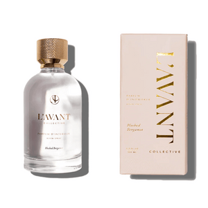 Clear glass bottle with a textured gold cap containing Room Spray | L'AVANT Collective, alongside its matching beige packaging with gold lettering, highlighting Blushed Bergamot scent.