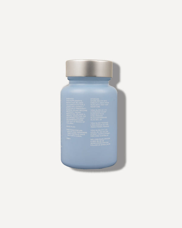 Blue frosted bottle with a silver cap showing the back label of Clear Capsules | VIDA GLOW, a wellness supplement product.