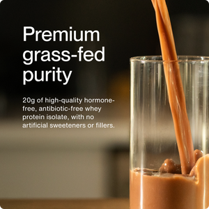 Close-up of creamy chocolate whey protein isolate being poured into a clear glass, highlighting 20g of premium grass-fed, hormone-free, antibiotic-free supplement with no artificial sweeteners or fillers.