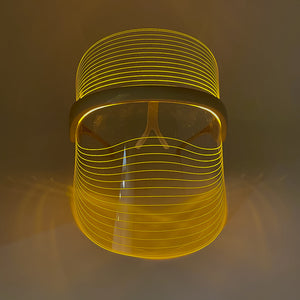 LED Light Therapy Visor | Vie Healing shown in a glowing yellow light, highlighting its sleek design for skincare and wellness device use.