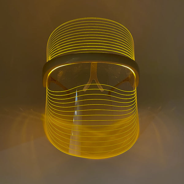LED Light Therapy Visor | Vie Healing shown in a glowing yellow light, highlighting its sleek design for skincare and wellness device use.