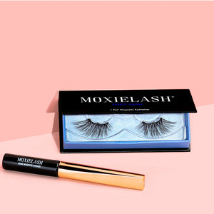 Pair of dramatic false eyelashes in a sleek black and blue case with a black and gold liquid magnetic eyeliner displayed on a pink background, featuring Foxy Lash | Moxielash.