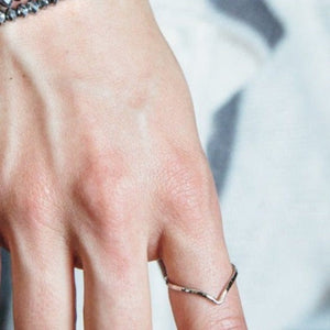 Close-up of a hand wearing a simple, elegant silver ring with a V-shaped design, showcasing the Journey Ring | Purpose Jewelry on the ring finger.