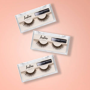 Three sets of false eyelashes displayed in clear plastic cases, each paired with a small tube of adhesive, presented on a soft pink background, featuring Lashies™ - Wifey - On The Go | Moxielash.