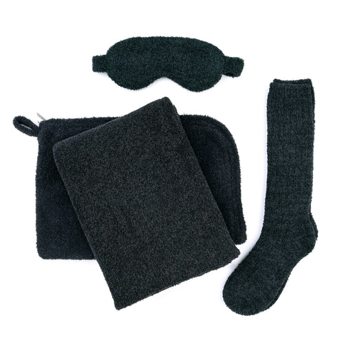 Soft black eye mask, cozy socks, plush blanket, and matching pouch arranged flat as part of the Travel Set (Blanket, Socks, Eyemask, Bag) | Kashwére for wellness and relaxation.