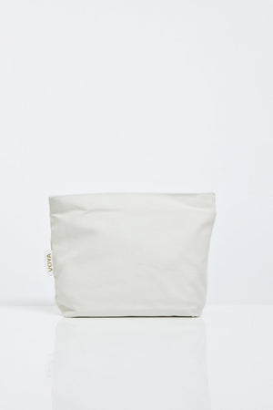 Minimalist natural fabric pouch in soft beige with a subtle VOYA tag, designed for convenient storage and travel in the Organic Voyager Travel Set | VOYA.