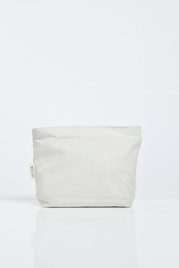 Minimalist natural fabric pouch in soft beige with a subtle VOYA tag, designed for convenient storage and travel in the Organic Voyager Travel Set | VOYA.