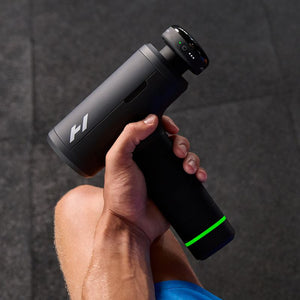 Person using a black Hypervolt 3 Pro | Hyperice percussion massage device on their leg for muscle recovery and body care with a glowing green light indicator on the handle.