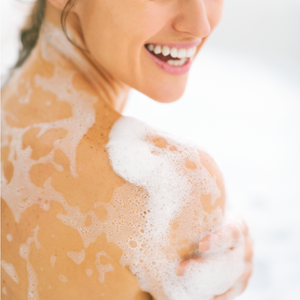 Smiling woman with soapy bubbles on her back using Cleansing Body Wash | Privai for a refreshing and gentle skincare experience.