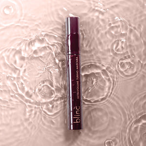 UltraVolume Tubing Mascara - Black | Blinc tube submerged in rippling water with soft pink lighting, highlighting a waterproof makeup product.