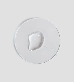 Clear gel-like drop of Essential Biphasic Makeup Remover | [ comfort zone ] on a smooth white surface representing gentle skincare and effective makeup removal.