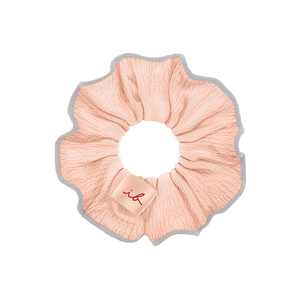 Light pink fabric hair scrunchie with a small beige tag featuring a red stylized logo, part of the Gift Set Nothing Can Stop Me 4 pc | invisibobble.