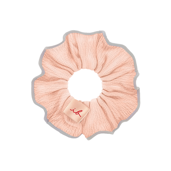 Light pink fabric hair scrunchie with a small beige tag featuring a red stylized logo, part of the Gift Set Nothing Can Stop Me 4 pc | invisibobble.