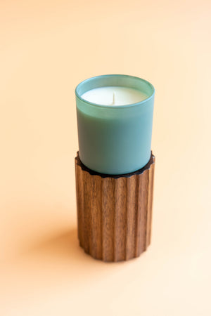 Evergreen + Eucalyptus Dignity Series Glass Jar Soy Candle | Calyan Wax Co. - 5.3 oz displayed in a light green frosted glass container on a wooden textured holder against a soft beige background.