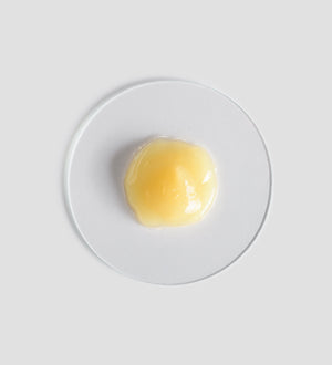 A small dollop of light yellow gel texture on a clear circular surface representing the Active Pureness Fluid | [ comfort zone ] skincare product.
