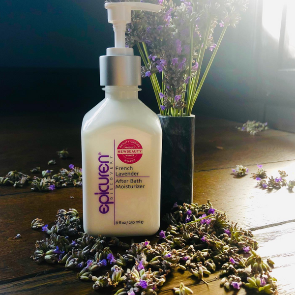 Bottle of French Lavender After Bath Moisturizer | Epicuren Discovery surrounded by dried lavender flowers with a vase of fresh lavender in the background on a wooden surface, highlighting skincare and body care.
