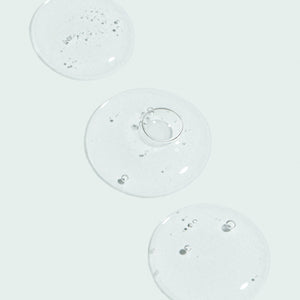 Clear gel droplets with small air bubbles on a light background representing the texture of AGLESS total pure hyaluronic 6 filler | IMAGE Skincare for skincare and wellness supplements.