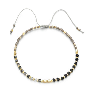 A delicate beaded bracelet featuring gray, black, and gold beads with an adjustable cord closure, crafted as part of the Japanese Handmade Bead Bracelets | Live Love Spa collection.