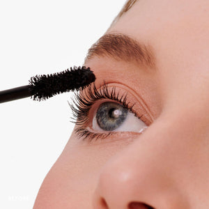 Close-up of a person applying Beyond Lash Volumizing Mascara | Jane Iredale to long eyelashes, enhancing eye definition with a volumizing brush.