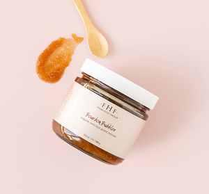 Jar of Bourbon Bubbler Liquor Infused Body Polish | Farmhouse Fresh with a wooden spoon and a sample of the exfoliating body polish on a pale pink background