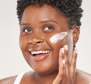 Woman smiling while applying Evening Rose Moon Dip® Ageless Facial Sleep Mousse with Peptides + Retinol | Farmhouse Fresh to her cheek as part of a skincare routine.