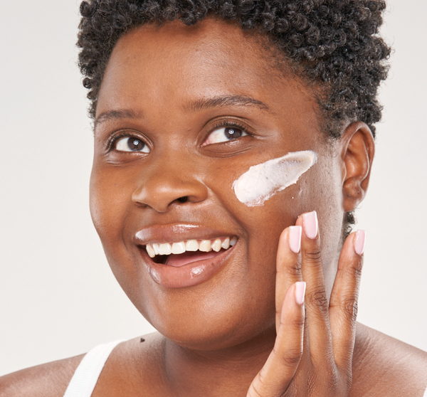 Woman smiling while applying Evening Rose Moon Dip® Ageless Facial Sleep Mousse with Peptides + Retinol | Farmhouse Fresh to her cheek as part of a skincare routine.